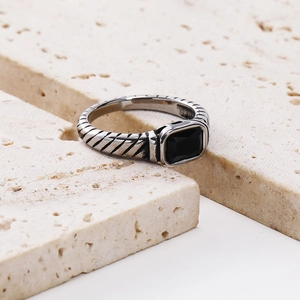 Macro view of a rectangular black gemstone ring with a twisted cable band design