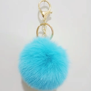 Close-up of bright blue 8cm faux rabbit fur pom pom keychain with gold metal lobster clasp