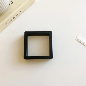 Minimalist square black PE film jewelry display box on a white desk with aesthetic decor