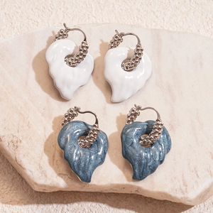 Leaf-shaped enamel hoop earrings in blue and white on stone background