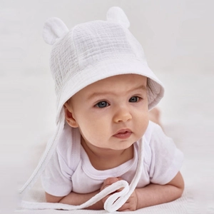 White cotton baby sun hat with cute bear ears and secure chin straps shown on a baby