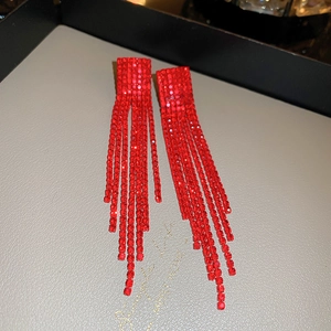 Detailed macro shot of long red tassel earrings with sparkling rhinestones on jewelry tray