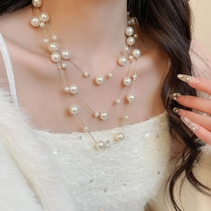 Macro view of triple-layer pearl necklace showing different bead sizes and gold chain