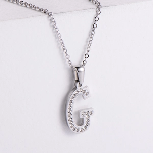 Detailed view of silver letter G pendant with sparkling pave rhinestones on chain