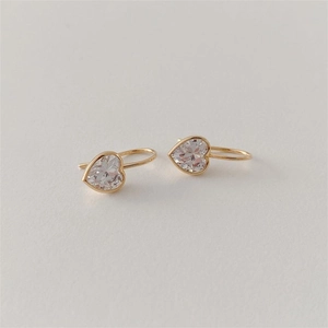 Elegant gold heart earrings with clear cubic zirconia on a minimalist cream background