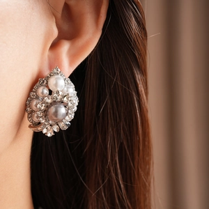 Detail of vintage palace style earrings with white and grey pearls on a model ear