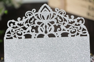 Macro detail of laser-cut floral pattern on glittery silver wedding invitation paper