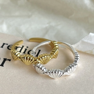 Detailed view of silver and gold scallop shell rings with adjustable open band design
