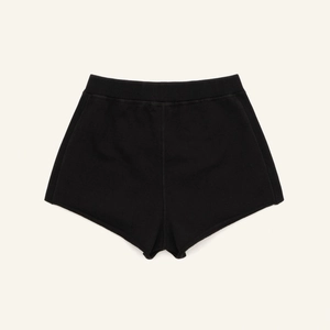 Gros plan à plat de ce short de sport en maille noir ajusté sur un fond crème doux