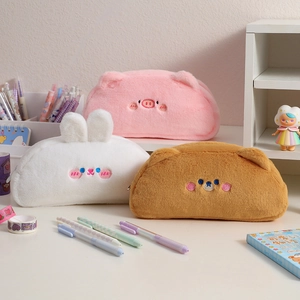 Three cute plush animal pencil cases in pig, rabbit and bear shapes on a white desk