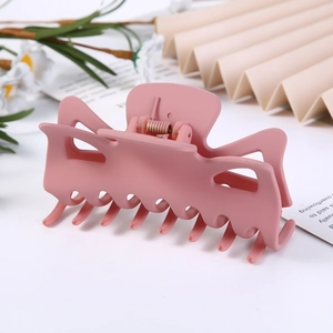 Pink matte hollow hair claw clip shown in a minimalist setting with soft lighting