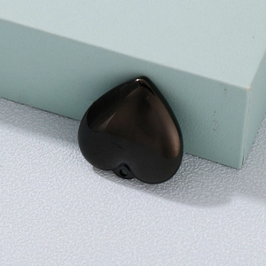 Polished black stainless steel heart pendant with hole on white textured background