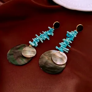 Bohemian style bamboo-shaped shell earrings with blue coral beads on velvet background