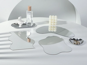 Artistic layout of irregular silver acrylic mirror trays on a table with soft shadows