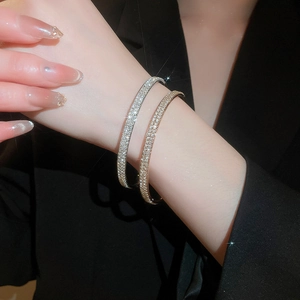 Close-up of gold and silver pavé crystal bracelets worn against a black blazer