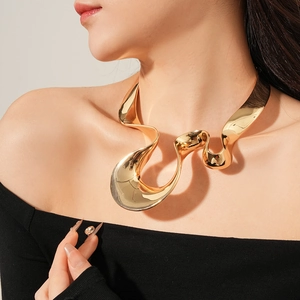 Close-up of golden streamlined metal collar necklace with an artistic twisted design