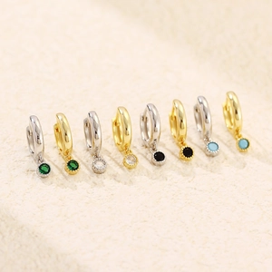 Macro detail of gold and silver S925 earrings with colorful round zircon pendants