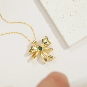 Detail of gold bow pendant with green zircon gemstone on a slim choker chain