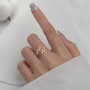 Detail of a golden leaf ring with sparkling zircons worn on a finger