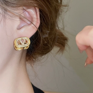 Detailed close-up of 18k gold-plated oval earrings featuring an elegant V logo and zircons