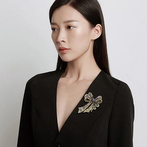 Elegant bow-shaped brooch with blue and gold crystals pinned on a model's jacket