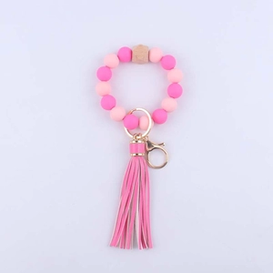 Detail of pink silicone beads wristlet with wooden bead and faux leather tassel charm