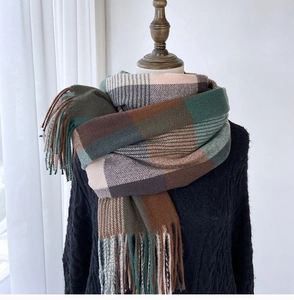 Detail shot of green and brown checkered scarf with long fringe on a mannequin