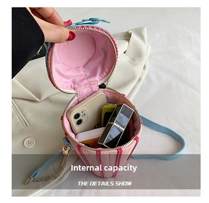 Detail showing internal capacity of the striped cylindrical crossbody bag for essentials