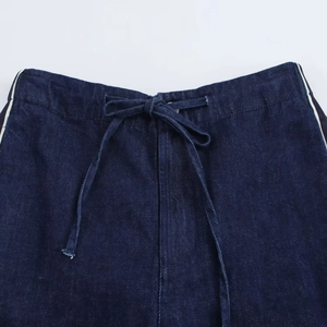 Dettaglio della vita con coulisse blu scuro con strisce bianche sui pantaloni denim