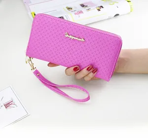 Detail showing fuchsia textured leather wallet with gold logo and wrist strap