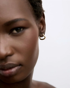 Close-up of 18k gold plated heart hoop earrings worn by a model in soft lighting