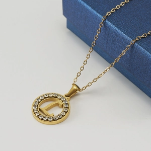 Collier en or 18 carats avec pendentif lettre L et cristaux sur un écrin bleu