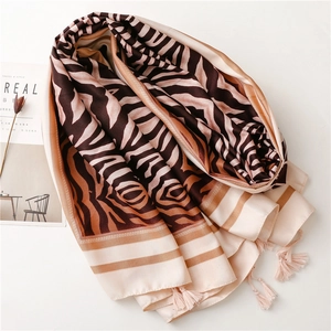 Detail of zebra pattern silk scarf with elegant tassels on a satin texture fabric
