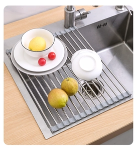 Roll-up stainless steel drying rack with grey silicone ends over a sink with fruits