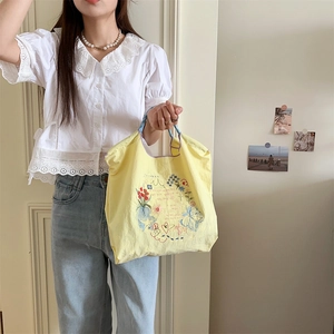 Détail de motifs floraux brodés et graffiti sur un sac cabas Oxford jaune vif