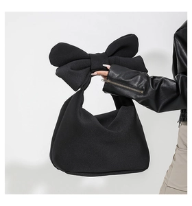 Close-up of a black padded nylon tote bag with a large decorative bow on the handle