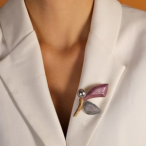 Detailansicht einer Emaille-Libellenbrosche mit Perlenkopf auf weißem Blazer