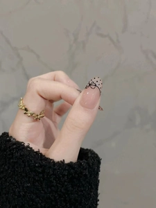 Detailed view of a gold butterfly ring paired with French polka dot bow press-on nails