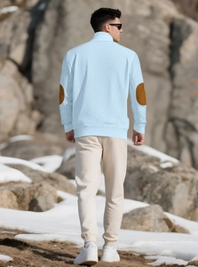 Detail of light blue knit sweater with brown elbow patches in a snowy outdoor scene