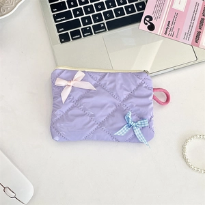 Flat lay of a light purple quilted cosmetic bag with decorative bows and zipper detail