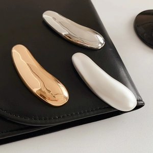 Detail of minimalist irregular liquid metal brooches in gold, silver and pearl finishes