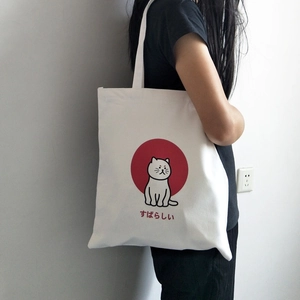 Detail of white canvas tote bag with cartoon cat print and Japanese text on model