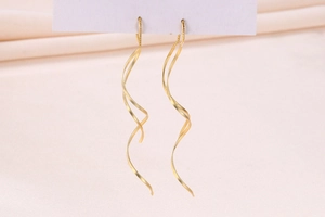 Macro shot of matte gold spiral threader earrings on elegant silk background