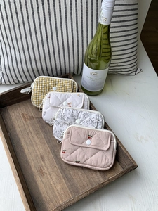 Quilted storage pouches in floral and checkered patterns on a rustic wooden tray