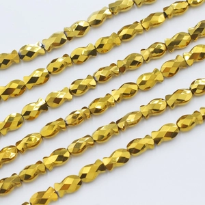 Macro shot of gold fish-shaped crystal beads with diamond-cut facets for DIY jewelry