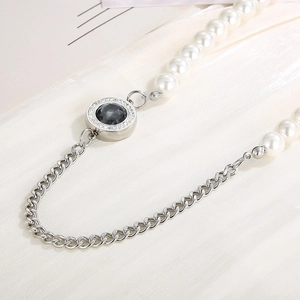 Detail of a hybrid necklace with white pearls and silver Cuban chain featuring a black gemstone