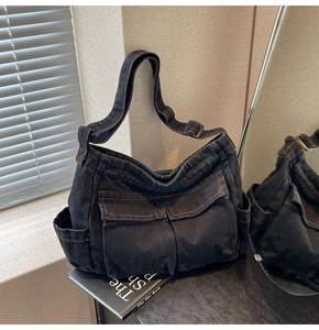 Detail of dark denim tote bag with orange contrast stitching and adjustable metal buckle