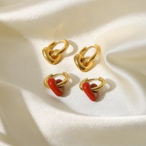 Détail de boucles d'oreilles créoles dorées 14K avec cœurs sur tissu en soie blanche