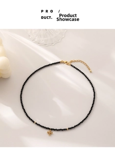 Close-up of black beaded necklace with a gold cross pendant and adjustable extender chain