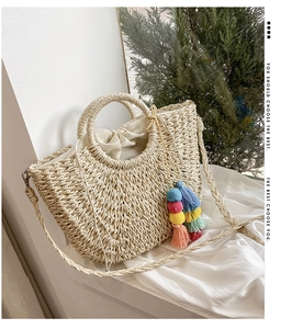 Close-up of woven straw bag with colorful tassels, ring handle and drawstring lining